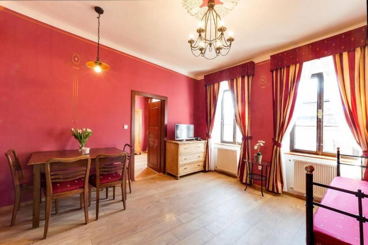Una habitación con una mesa de comedor de madera, sillas, un televisor, un mueble bajo y un radiador.