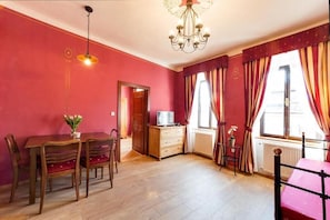 Una habitación con una mesa de comedor de madera, sillas, un televisor, un mueble bajo y un radiador.