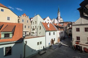 A narrow street with buildings, a church steeple, and a clear blue sky.