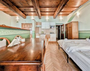 A room with a wooden dining table, a bed, a kitchenette, and a bathroom. - Apartments Kajovska (Ceský Krumlov)