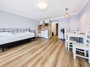 A room with a bed, a small kitchenette, a dining table with chairs, and a ceiling fan. - Apartments Kajovska (Ceský Krumlov)