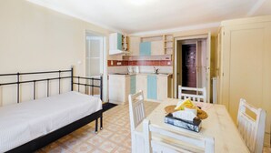 A compact room with a bed, a dining table with chairs, a kitchenette, and a bathroom door. - Apartments Kajovska (Ceský Krumlov)