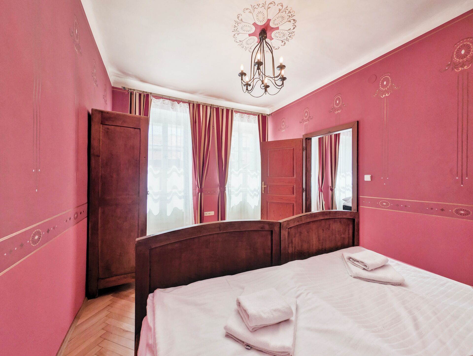 Ein Schlafzimmer mit einem Bett, einem Holzschrank, einem Spiegel und einer Chandelier.