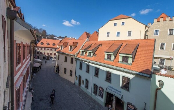 A narrow cobblestone street lined with historic buildings, some with visible signage indicating commercial use. - Apartments Kajovska (Ceský Krumlov)