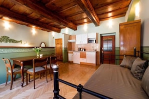 Una habitación acogedora con techo de madera, una mesa de comedor con sillas, una cama y un kitchenette.