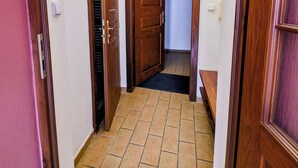 A narrow hallway with wooden doors and a tiled floor. - Apartments Kajovska (Ceský Krumlov)