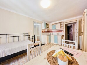 A compact room with a bed, a small dining table, and a kitchenette. - Apartments Kajovska (Ceský Krumlov)