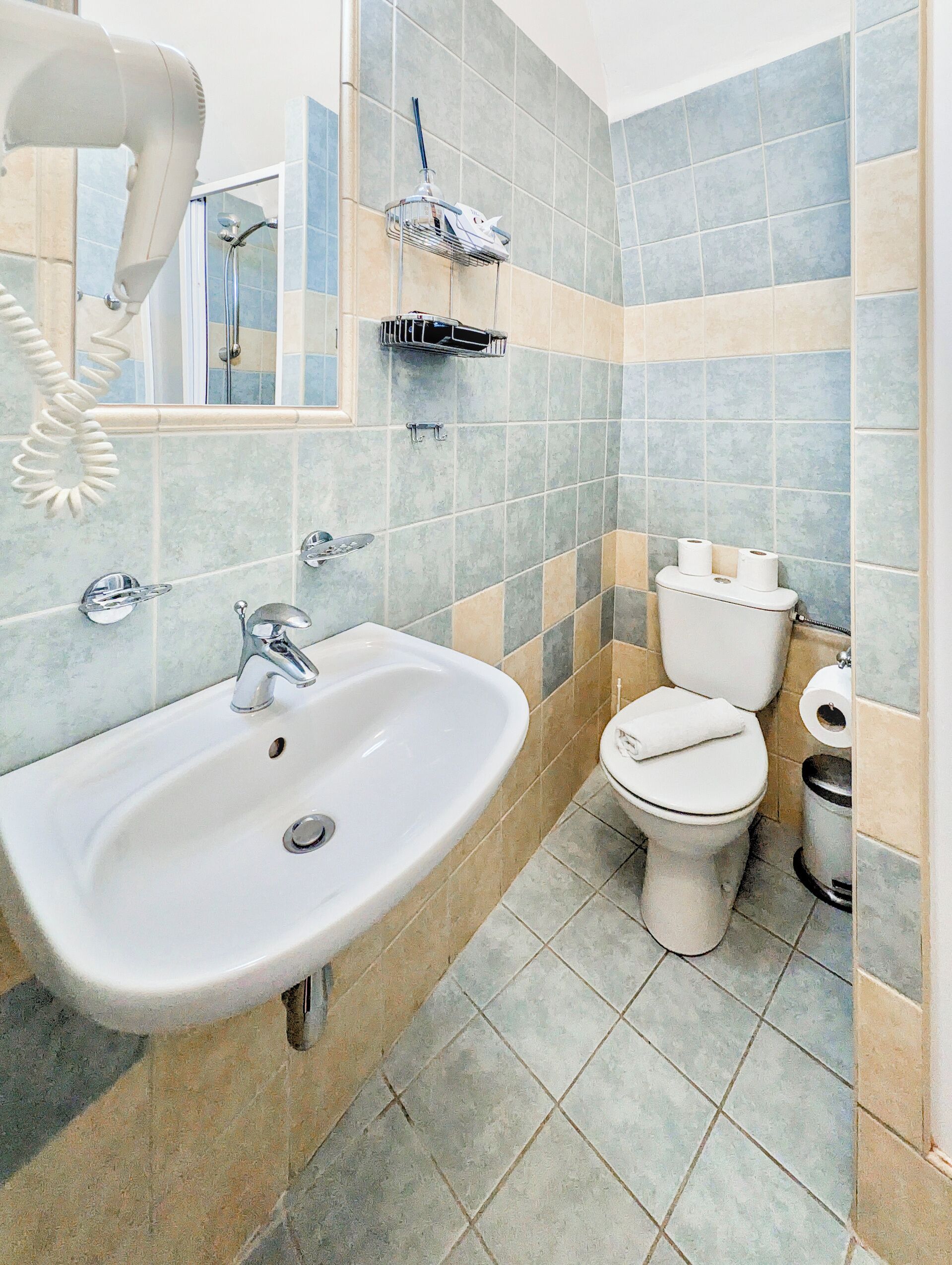 A bathroom with a sink, toilet, and a mirror.