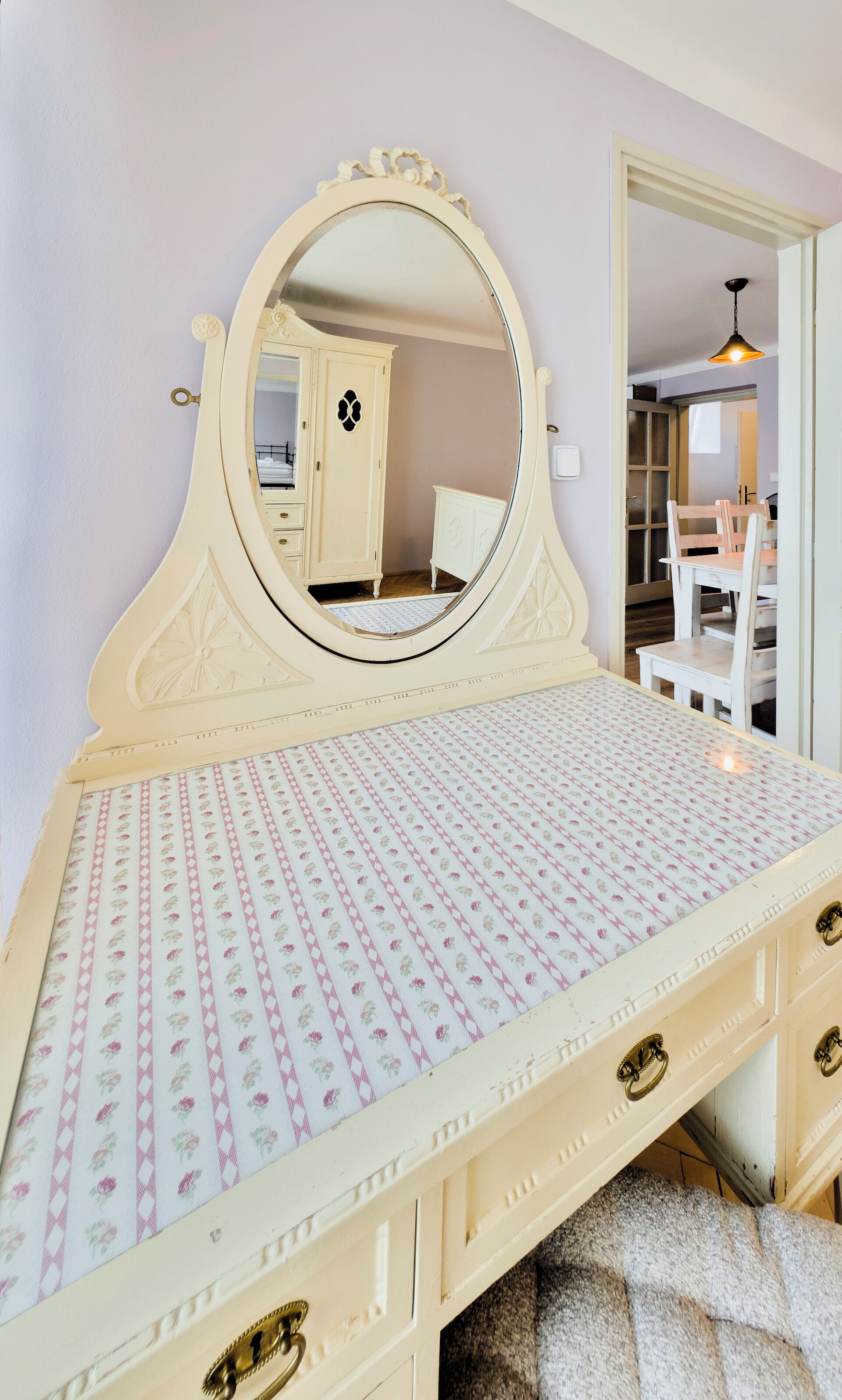 Una tocador de estilo vintage con un espejo grande, colcha estampada y varios cajones.