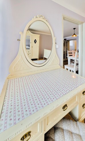 Una tocador de estilo vintage con un espejo grande, colcha estampada y varios cajones.