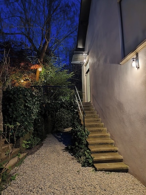 A staircase leading to a building entrance, surrounded by gravel and vegetation.