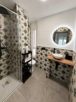 Une salle de bain Ă©quipĂ©e dâune douche, de toilettes, dâun lavabo et dâun miroir.