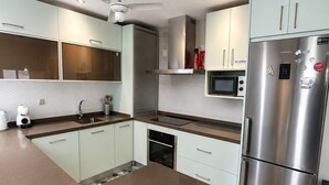 Et moderne køkken med et rustfrit stål køleskab, en mikroovn og en loftventilator.