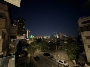 A nighttime cityscape with buildings, a street, and parked cars. - 201 JRE Apartment With Stunning Boulevar (Amman)