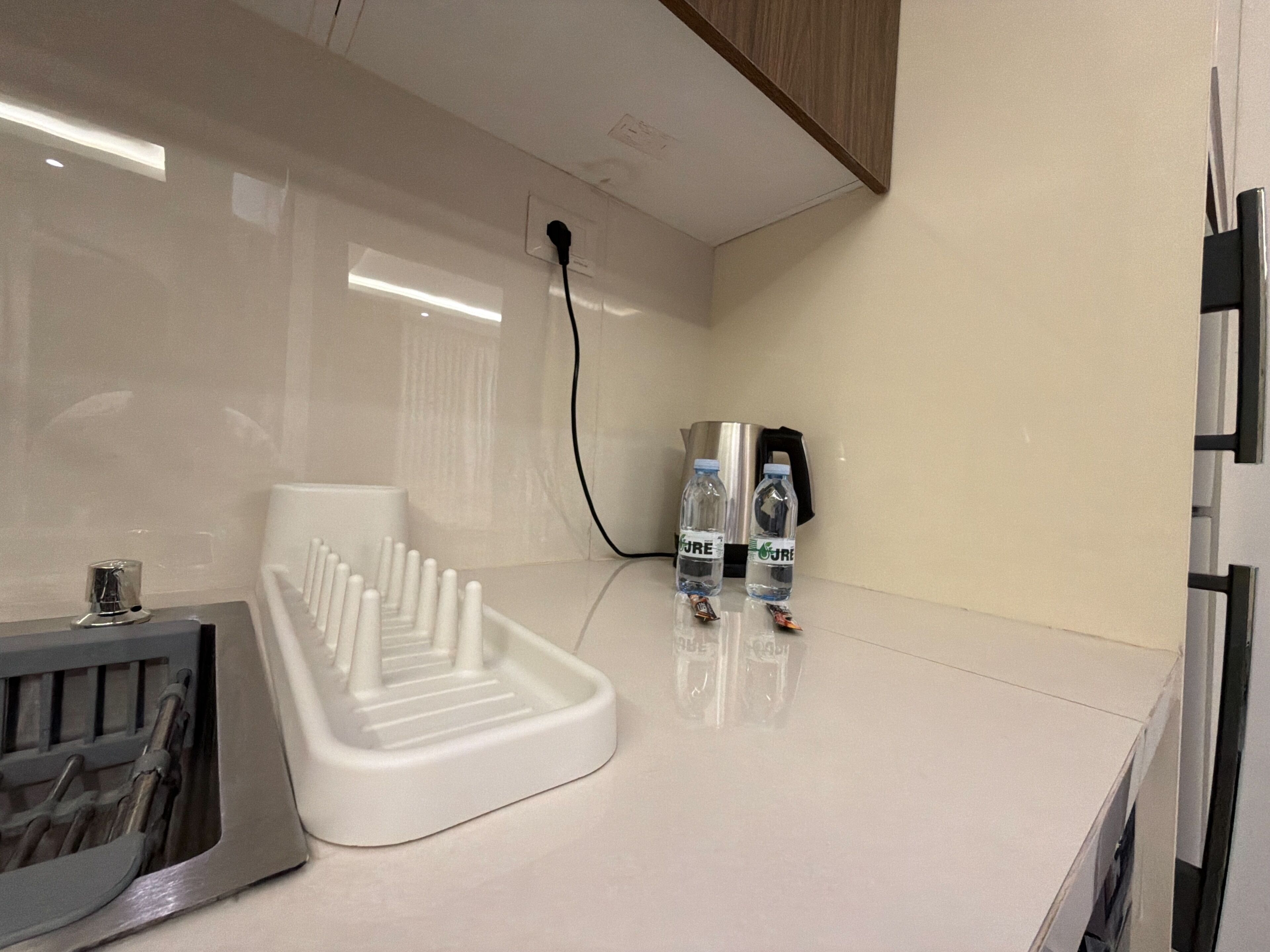 A kitchenette with a white sink, a kettle, and two water bottles on the counter.