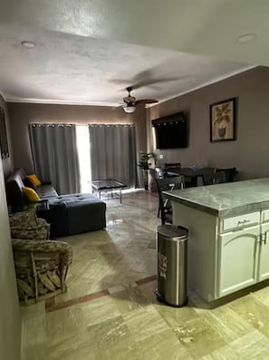Ein modernes Wohnzimmer mit einer Couch, einem Esstisch und einer Küchenzeile mit Marmorarbeitsplatte.
