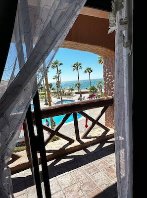 Blick auf einen Poolbereich mit Palmen und blauem Himmel.