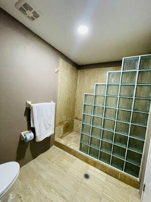 Ein Badezimmer mit Dusche, Toilette und Handtuchhalter.