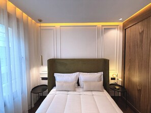 A neatly made bed with white linens, a green upholstered headboard, and two bedside tables with lamps. - Cosy apartment in the center of Marrakech (Marrakech)