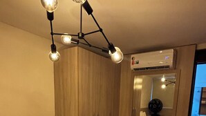 Une chambre d’hôtel avec un lit, une armoire en bois, un miroir et un luminaire au plafond.