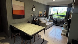Un salon moderne avec une table à manger, un canapé et un hamac près de la fenêtre.