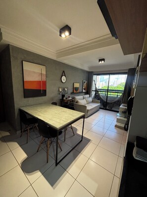 A modern living room with a dining table, sofa, and a hammock by the window. - Bellenus - balcony, hammock, comfort. (João Pessoa)