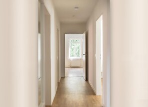 A narrow hallway with a wooden floor leading to a door with a window. - Helga's Stadthaus | vacation apartment, business apartment & temporary apartment in Nordhorn - Pets welcome (Nordhorn)