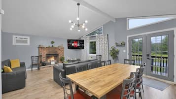 A spacious living area with a fireplace, a large wooden dining table, and a comfortable seating arrangement.