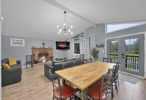 A spacious living area with a fireplace, a large wooden dining table, and a comfortable seating arrangement. - Poconos Chalet, Game Room, Hot Tub & Firepit (Tobyhanna)