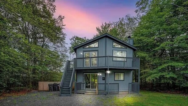 A two-story house with a balcony, a staircase, and a gravel driveway. - Poconos Chalet, Game Room, Hot Tub & Firepit (Tobyhanna)