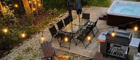 An outdoor patio with a fire pit, seating, and a hot tub.
