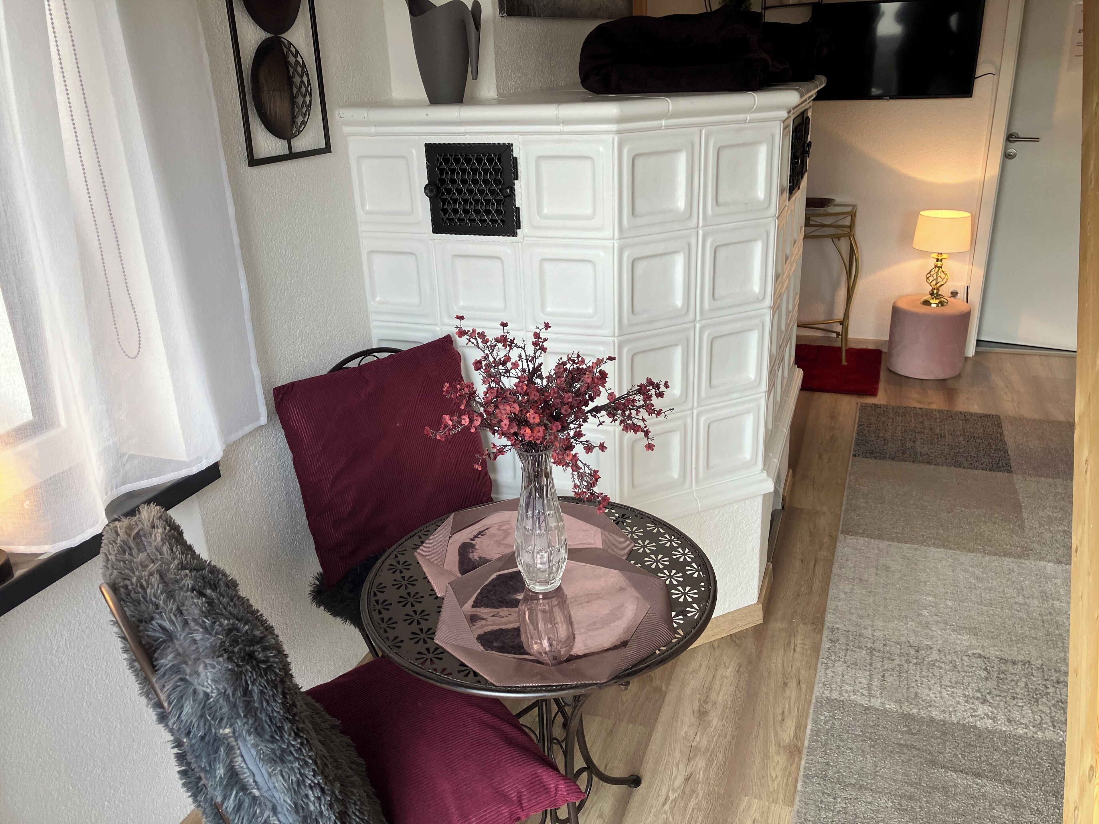 A room with a white cabinet, a round table with a vase, and a red pillow.