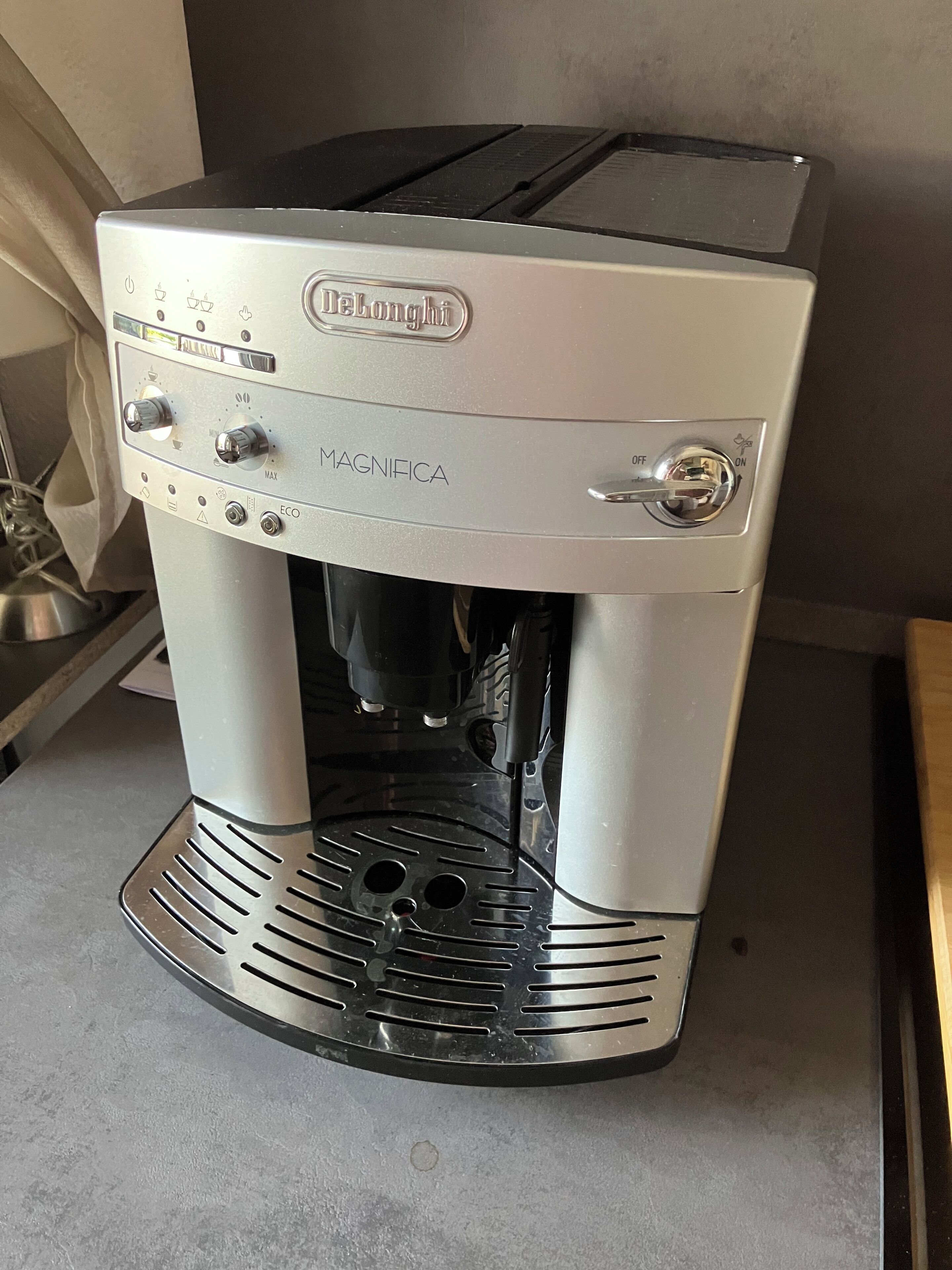 Une machine à expresso DeLonghi Magnifica dotée de boutons de commande, d’un réservoir d’eau et d’un bac de récupération.