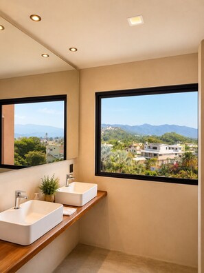 Ein modernes Badezimmer mit zwei Waschbecken, einem großen Spiegel und Blick auf eine Stadtkulisse durch große Fenster.
