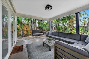 A covered outdoor patio with a sofa, a bench, and a small table.