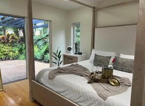 Une chambre à coucher avec un lit, une table de chevet et une vue sur un jardin.