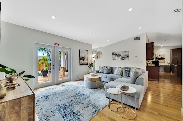 A modern living room with a grey sofa, a coffee table, and a large window with an outdoor view.