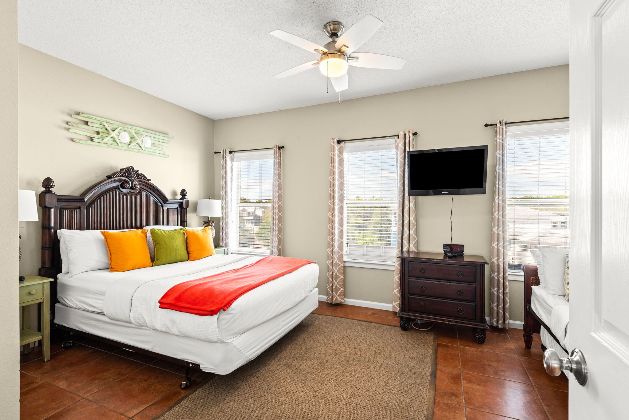 A bedroom with a bed, a ceiling fan, a TV, and a dresser.