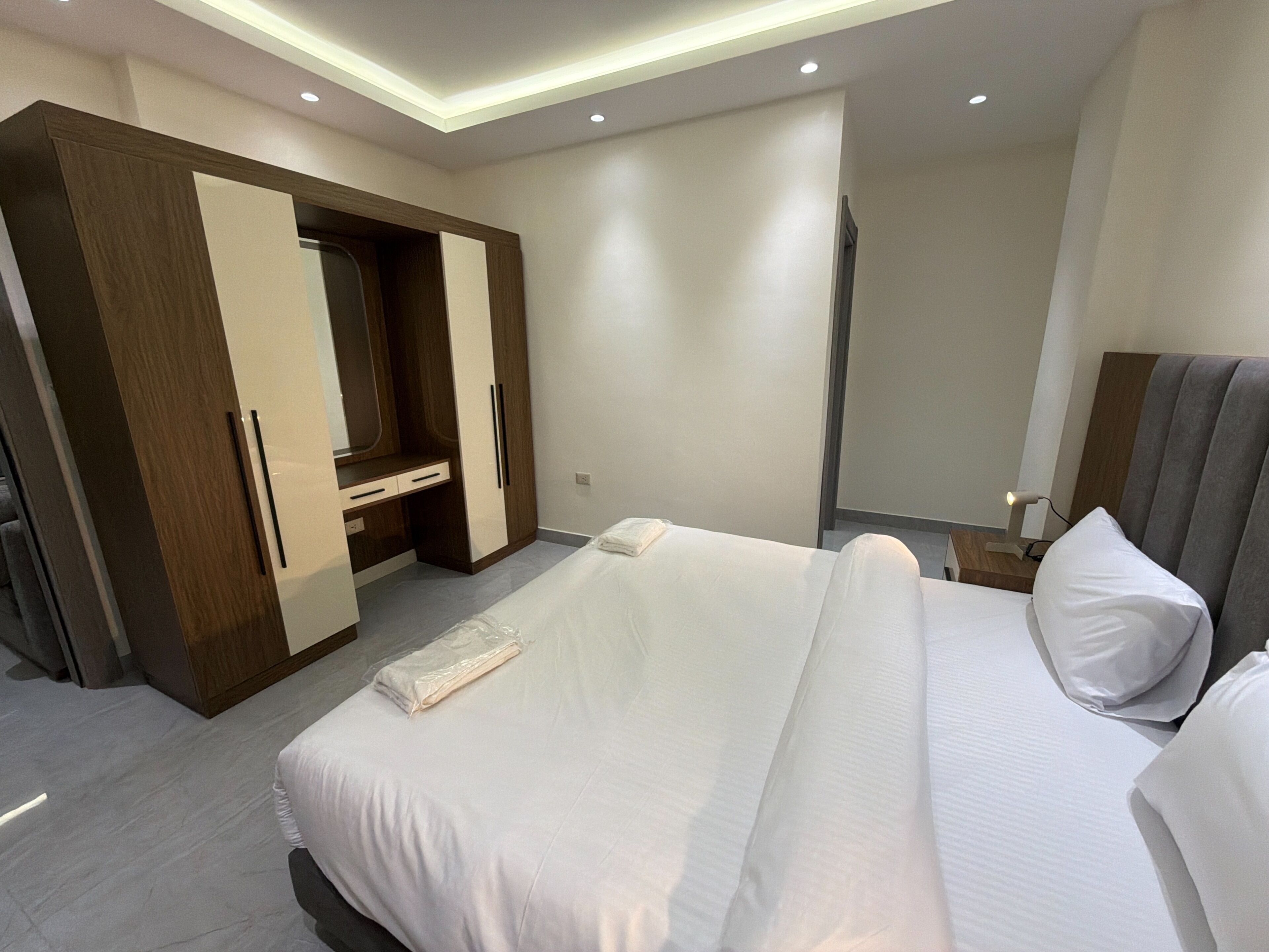 Una camera d'hotel moderna con un letto grande, un armadio, una scrivania e uno specchio.