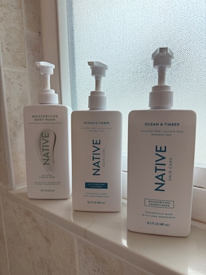 Three bottles of Native hair care products on a windowsill.