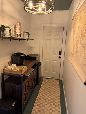 Un pasillo con una mesa de madera, un microondas, un refrigerador y una puerta con un mapa en la pared.