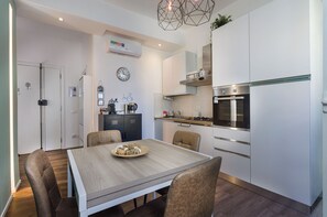Eine moderne Küche mit weißen Schränken, einem eingebauten Backofen und einem Essbereich mit einem Holztisch und Stühlen.