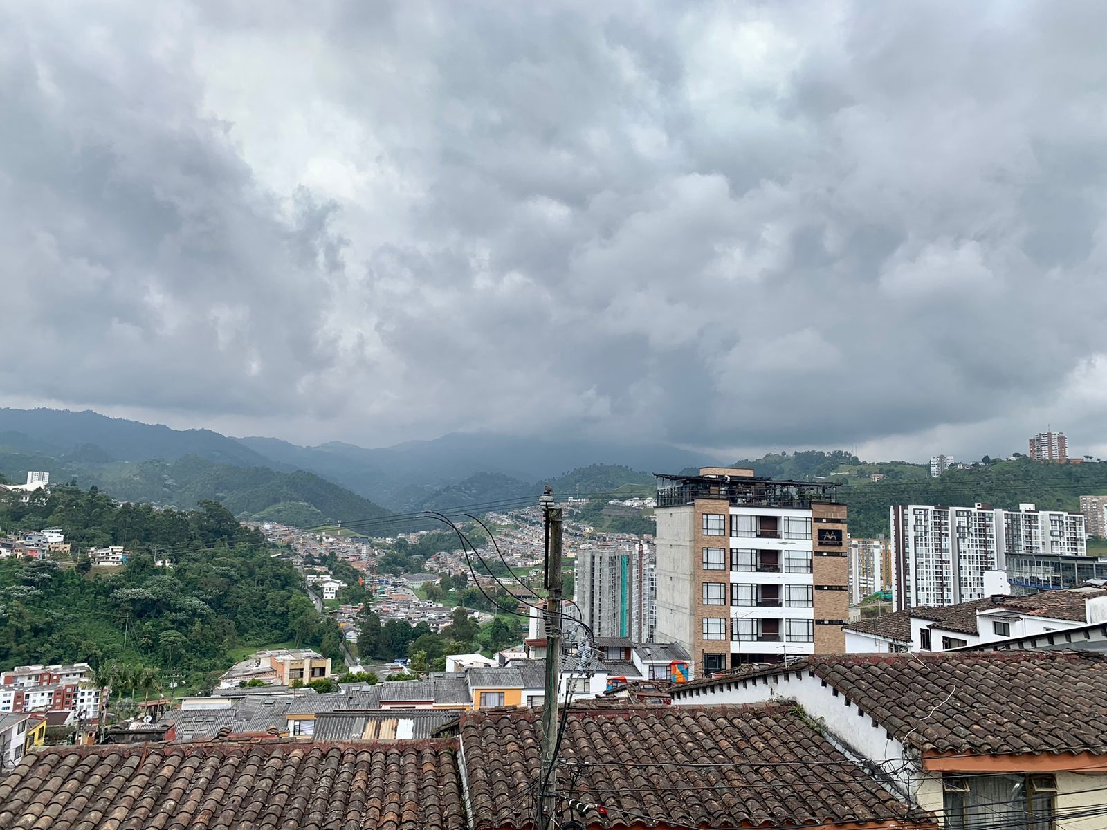 A cityscape with a mix of modern and traditional architecture, including a prominent building with a flat roof and a smaller structure with a sloped roof.