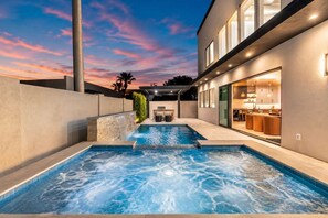 Ein modernes Haus mit Schwimmbad und einer Terrassenfläche.