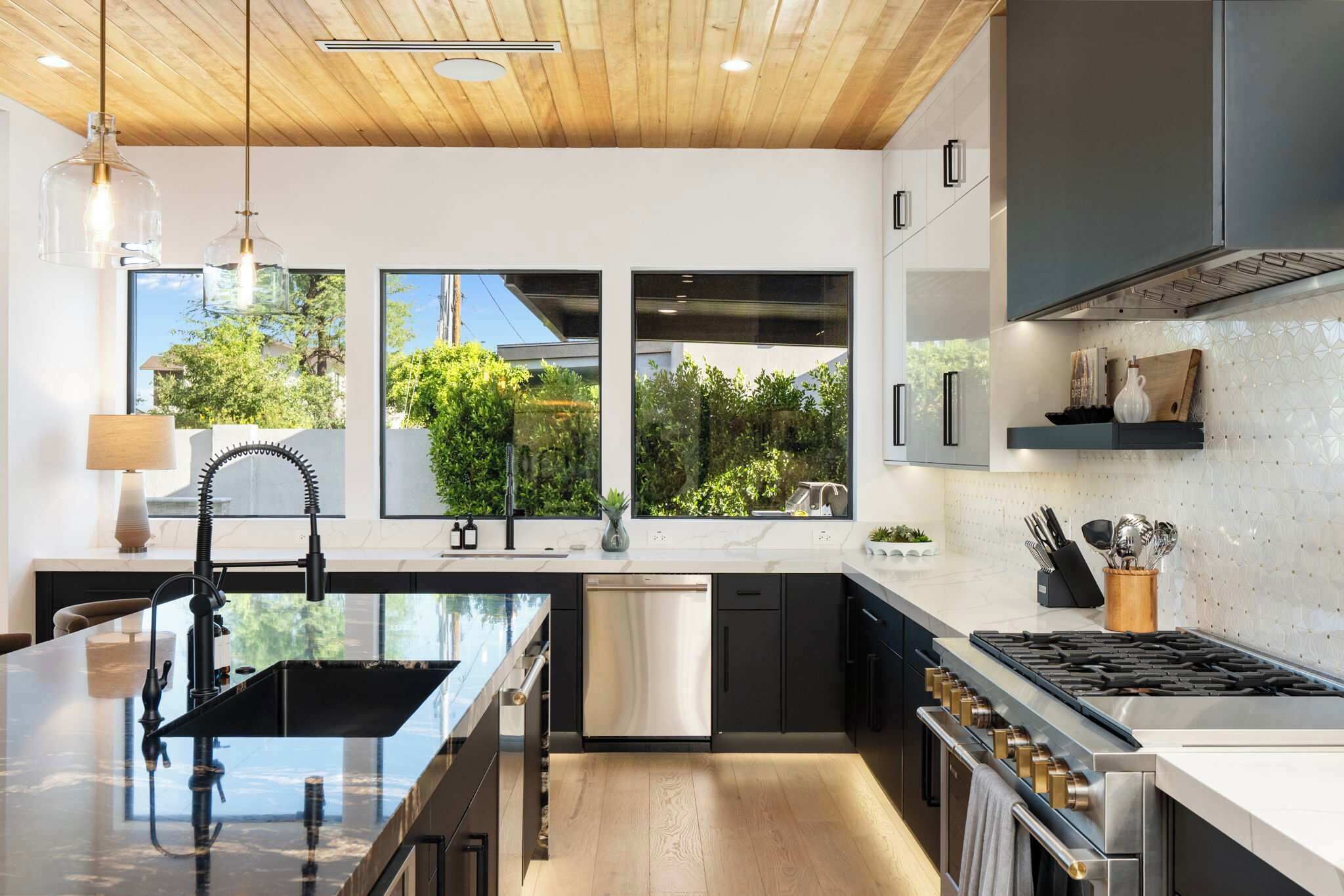 Una cocina moderna con una isla central, electrodomésticos de acero inoxidable y ventanas amplias que dan a zonas verdes.