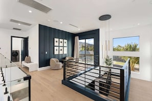 A modern living room with a staircase, a sofa, a coffee table, and a view of the outdoors. - NEW| Villa Solara - Old Town Ultra-Luxe Estate (Scottsdale)