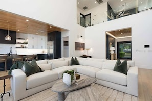 A modern living room with a sectional sofa, a coffee table, and a kitchen in the background.