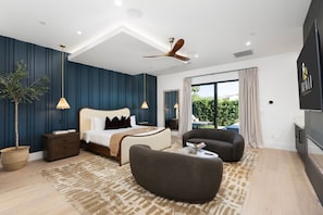 Ein modernes Schlafzimmer mit einem Bett, Nachttischen, einem Deckenventilator und einem großen Fenster.