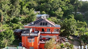 A multi-story building with solar panels, a balcony, and a car parked nearby. - West Breeze (Port Antonio)