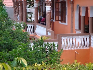 A building with columns, balconies, and a person sitting on a balcony.